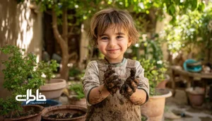 کودک در حال گل‌بازی زیر درخت توت در باغچه خانه، دستان گِلی و لبخند روشن.بازی‌های کودکی در باغچه