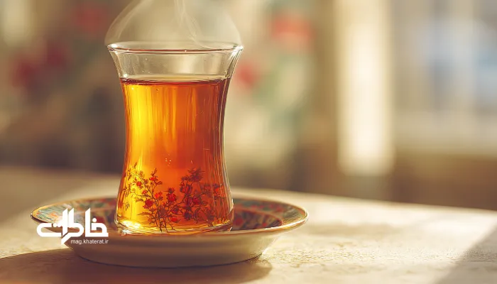 کلوزآپ استکان چای ایرانی با بخار ملایم در نور طبیعی و نعلبکی گلسرخی.چای دورهمی