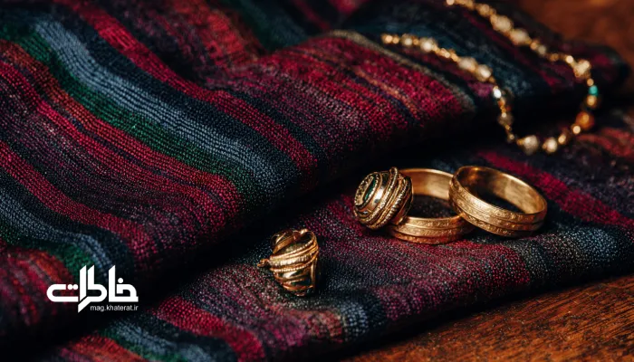 نمای نزدیک از دستمال یزدی تیره با رنگ‌های زرشکی و لاجوردی که پر از طلاهای درخشان و زیورآلات سنتی ایرانی است