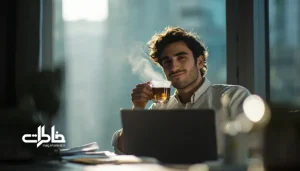 جوانی در روز کاری شلوغ پشت میز کار در حال نوشیدن چای با لبخند آرام و حس تمرکز. چای و کار