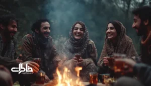 جمع دوستان ایرانی نشسته به‌صورت دایره دور آتش، با فنجان‌های چای در دست و نور روشن عصرگاهی. چای دور آتش