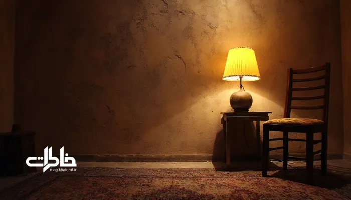 اتاق نیمهتاریک با آباژور زرد و سایههای نرم روی دیوار گچی؛ فضایی آرام، گرم و شاعرانه در خانه ایرانی. روانشناسی نور گرم