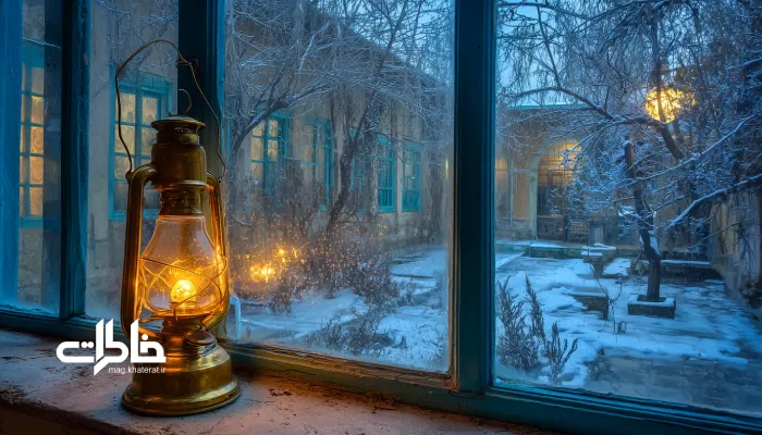 شب‌های زمستان با چراغ نفتی. چراغ نفتی روشن روی طاقچه در شب برفی زمستانی؛ حیاط ایرانی بیرون از پنجره پوشیده از برف، تضاد گرما و سرما و حس صمیمیت خانه‌های قدیمی