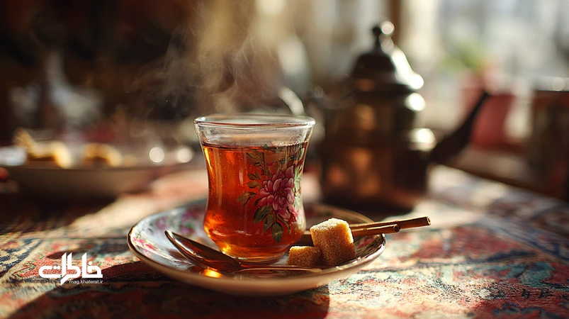 استکان چای دارچینی در نعلبکی گلسرخی روی سفره ایرانی؛ نماد مهماننوازی ایرانی و عصرانه مادربزرگها با بخار چای و حالوهوای نوستالژی.مجله خاطرات