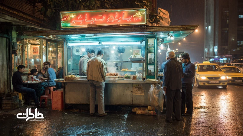 صحنهٔ شبانهٔ ساندویچ کثیف کنار خیابان در تهران با صف مشتری‌ها، نور نئون، بخار روغن داغ و خوردن روی جدول؛ آیین شهری و خاطره‌انگیز.