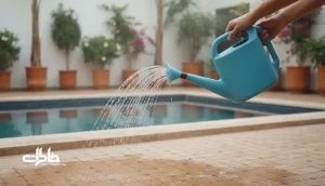 آب پاش پلاستیکی در حال آب پاشی حیاط خانه ایرانی برای خنک کردن کف در ظهر داغ تابستان
