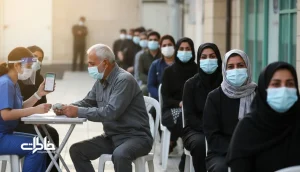 صف واکسن در ایران با تمرکز بر چشم‌هایی که پشت ماسک لبخند می‌زنند؛ فضای درمانگاه، صندلی پلاستیکی و حس امید و اضطراب
